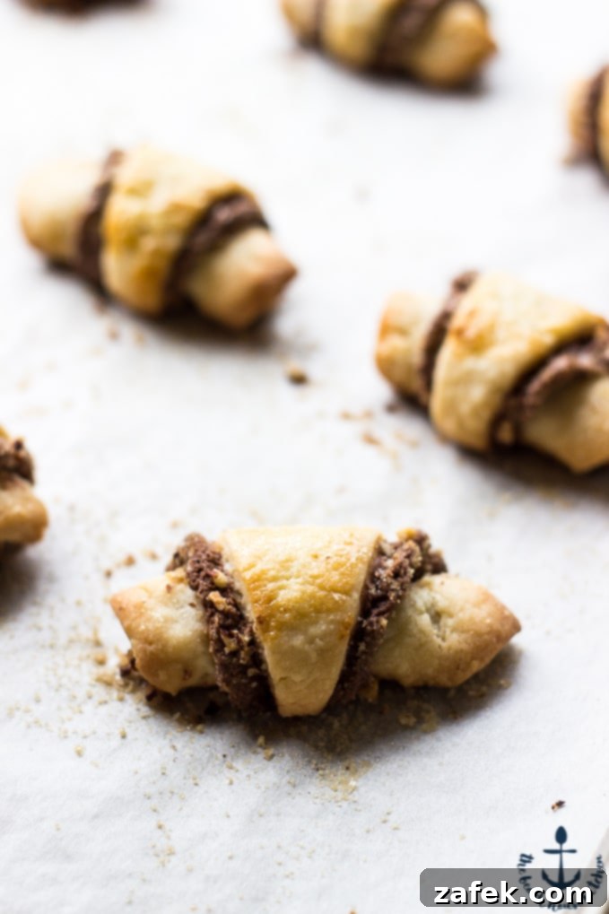 Nutella-Pecan-Rugelach Rolled Nutella Pecan Rugelach on parchment lined baking sheet after baking.