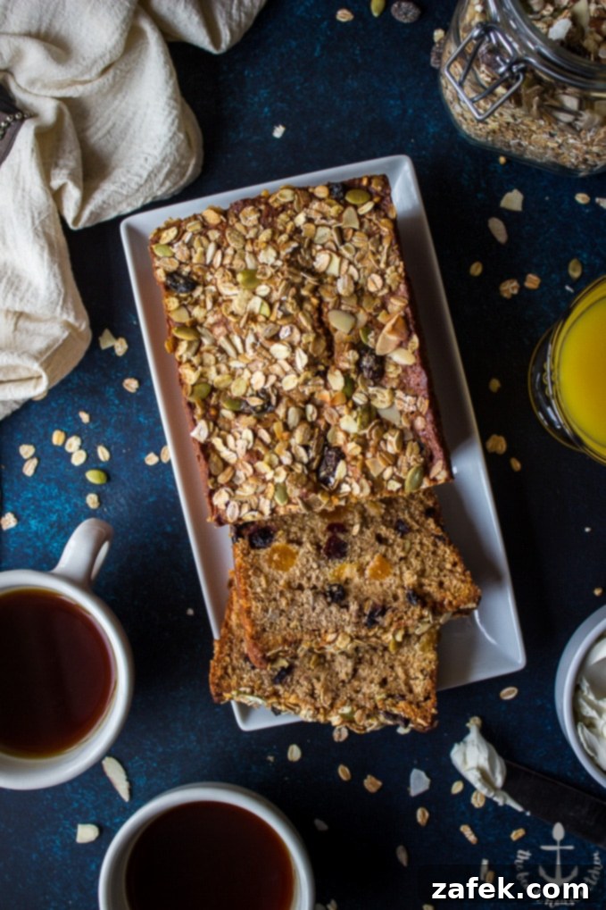 Loaded-Muesli-Quick-Bread Overhead shot of Loaded Muesli Quick Bread on a blue board with two coffee cups, a glass of orange juice, and a jar of muesli.