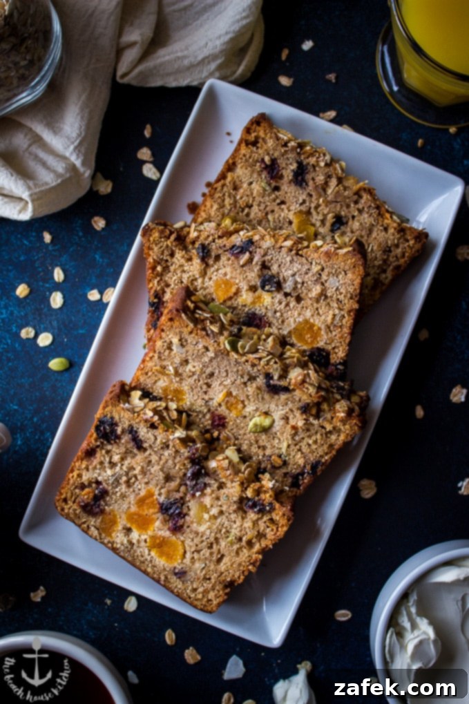 Loaded-Muesli-Quick-Bread Overhead shot of four slices of Loaded Muesli Quick Bread on a white rectangular plate.