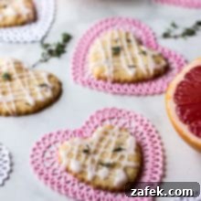 Pink Grapefruit and Thyme Shortbread Hearts on heart doilies with thyme leaves and pink grapefruit in background.