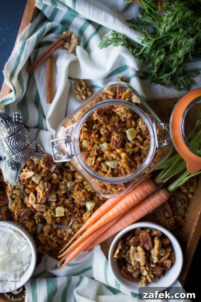 Carrot-Cake-Granola Overhead shot of carrot cake granola in jar on tray with bowls of nuts and coconut, carrots, and scooper filled with granola.