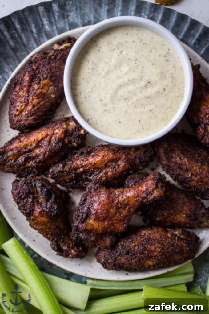 Baked-Spicy-Dry-Rub-Wings-White-BBQ-Sauce Overhead shot of spicy baked spicy wings with white bbq sauce on tray with celery.