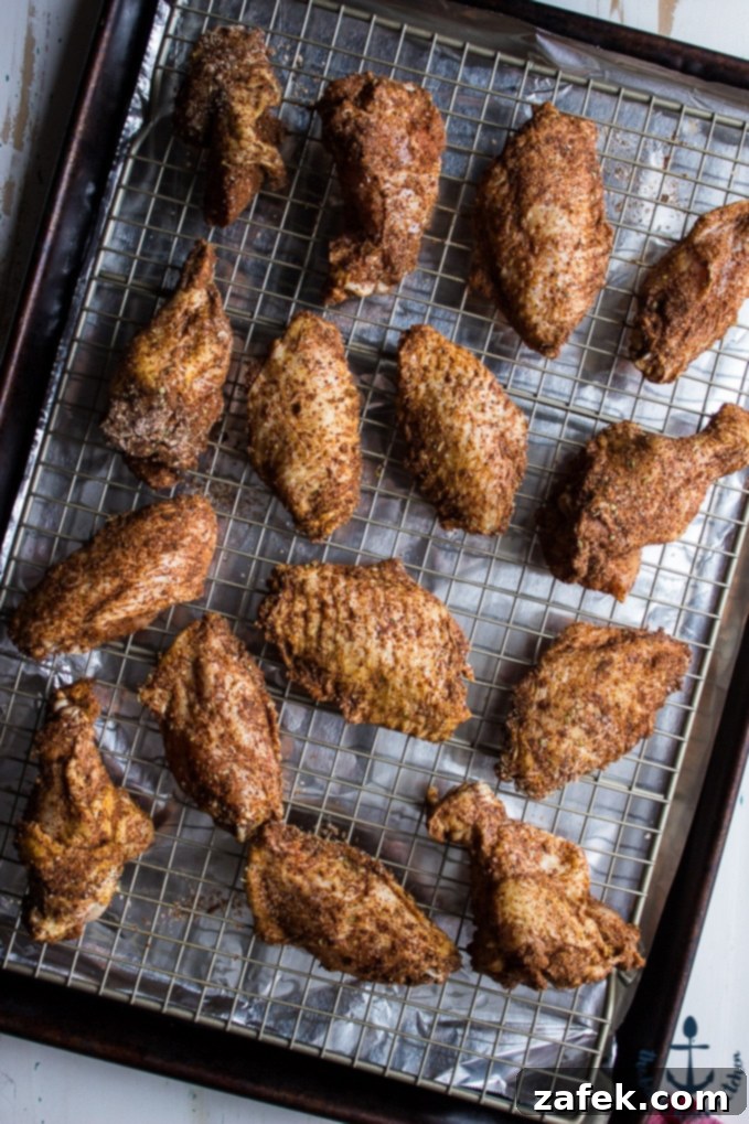 Baked-Spicy-Dry-Rub-Wings-White-BBQ-Sauce Overhead shot of spice rubbed wings on wire rack on baking sheet lined with foil.