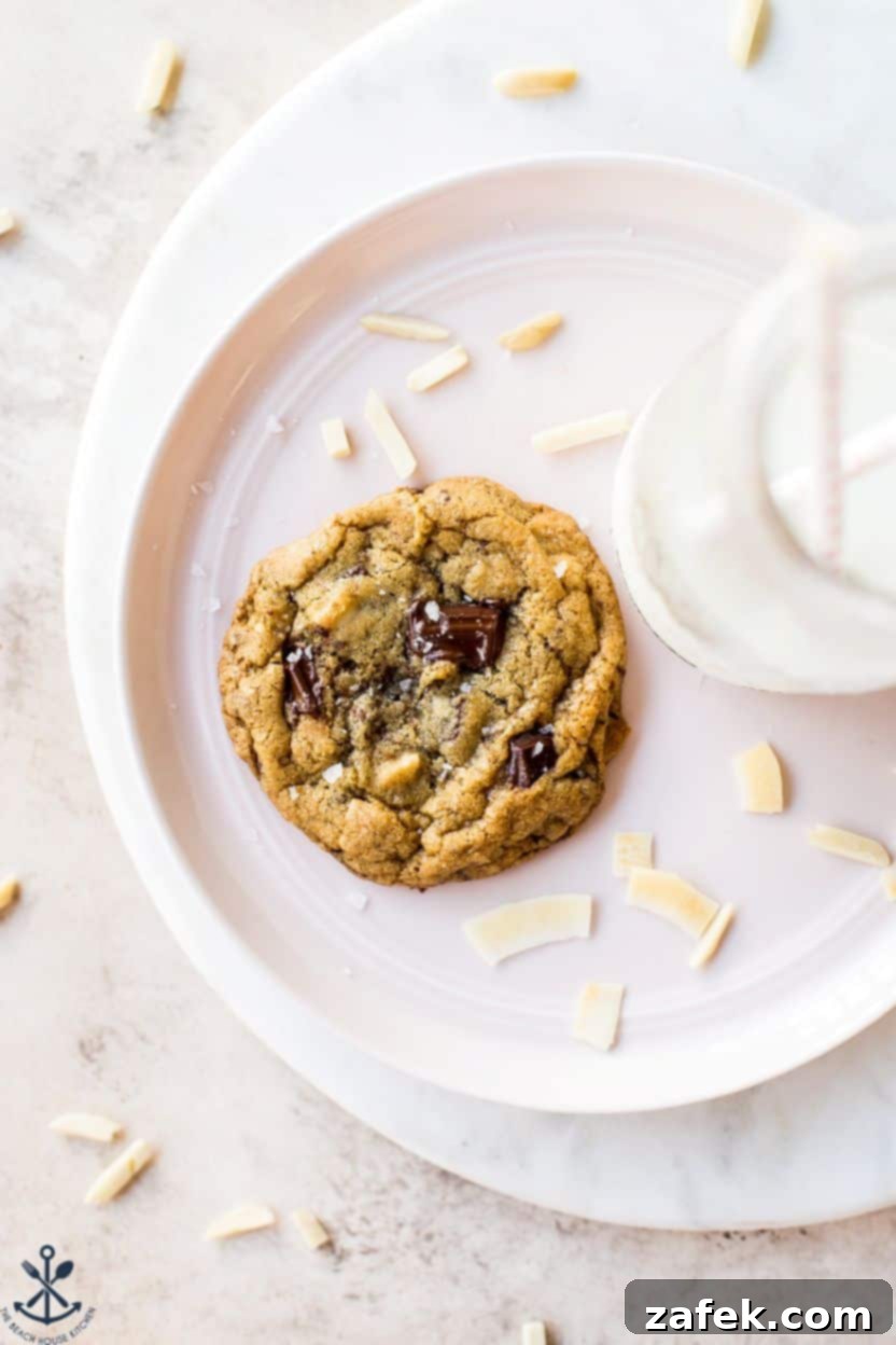 Coconut Almond Chocolate Chip Bliss Cookies 8 Overhead photo of an almond joy chocolate chip on a plate with some coconut flakes and a bottle of milk