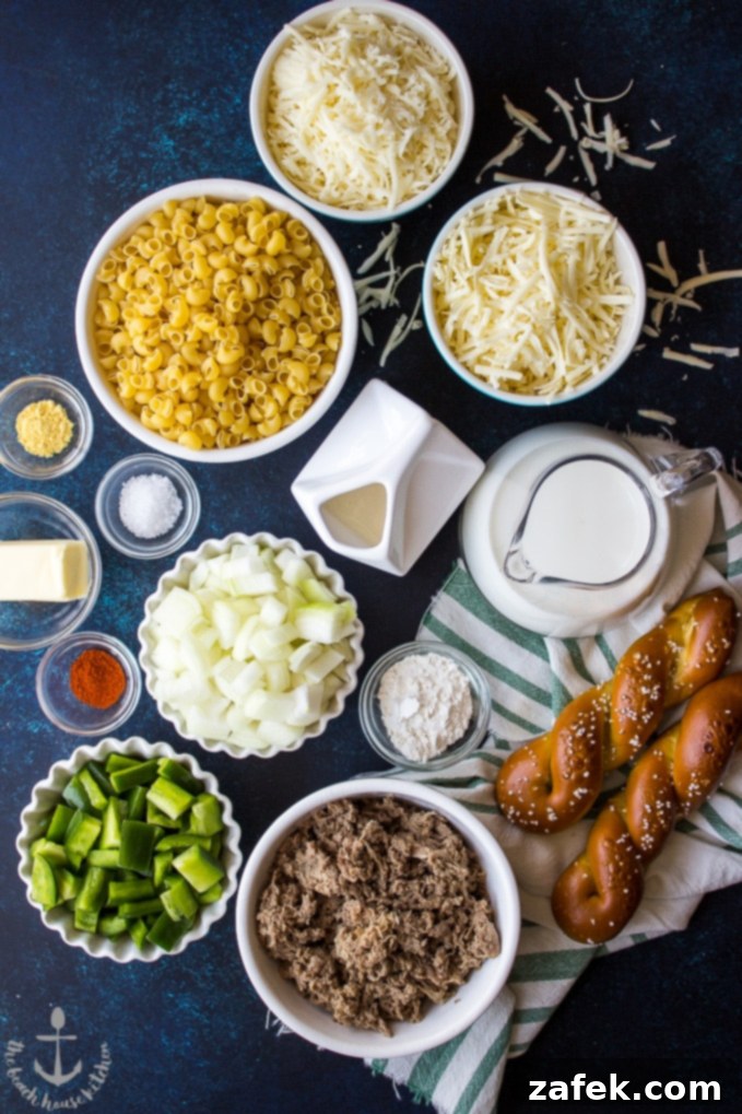 Various ingredients for Philly Cheesesteak Macaroni and Cheese laid out in individual bowls, including pasta, cheese, steak, and vegetables, ready for preparation.