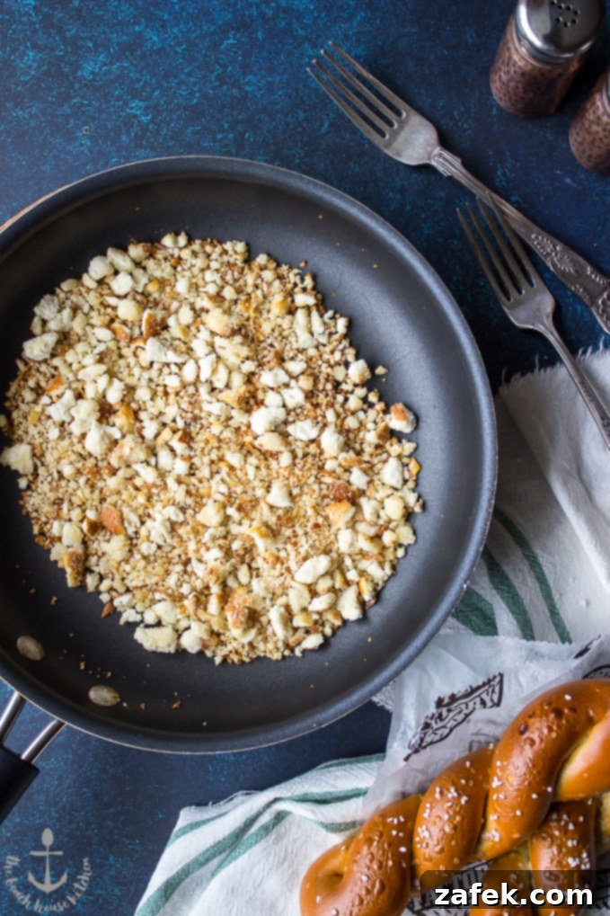 A skillet filled with golden-brown toasted soft pretzel crumbs, showcasing the final touch that makes this mac and cheese uniquely Philly.