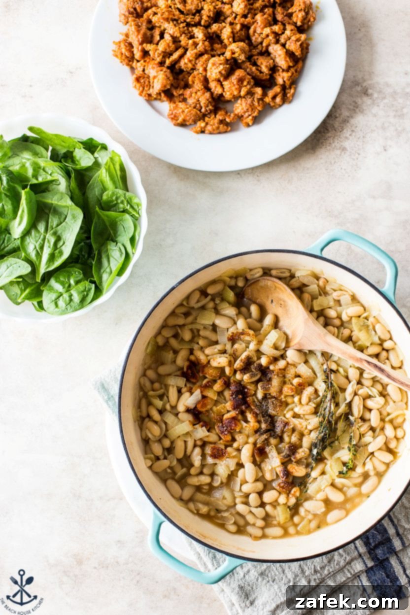 Hearty Chorizo and White Bean Stew 6 A selection of ingredients for White Bean and Chorizo Stew, including cooked crumbled chorizo, cannellini beans, and fresh spinach