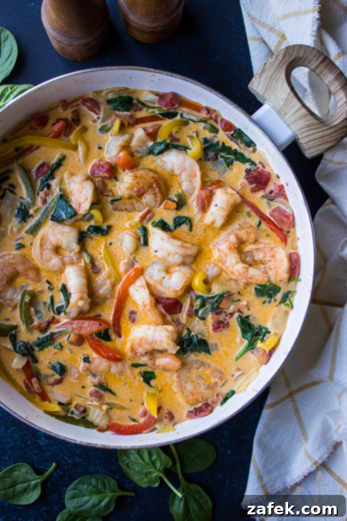 Cajun Shrimp Linguine Overhead photo of Cajun Shrimp Linguine in skillet with a white and yellow check dish cloth and a wooden salt and pepper shaker.