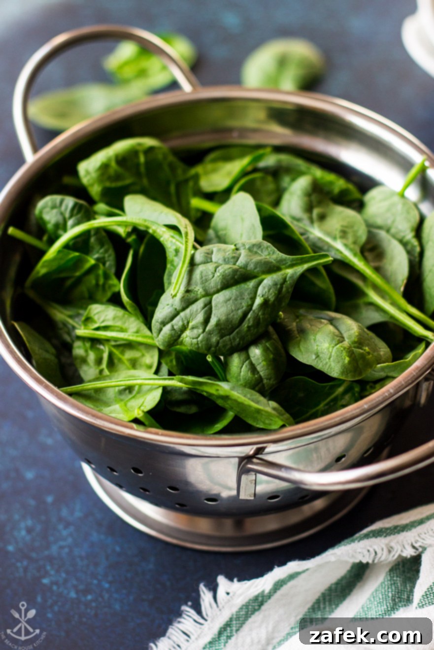 A colander filled with vibrant green baby spinach leaves, recently washed