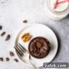 Decadent Double Chocolate Brownie Cupcakes 2 An overhead photo of a Double Chocolate Brownie Cupcake on a white plate with a silver fork and a bottle of milk with two straws