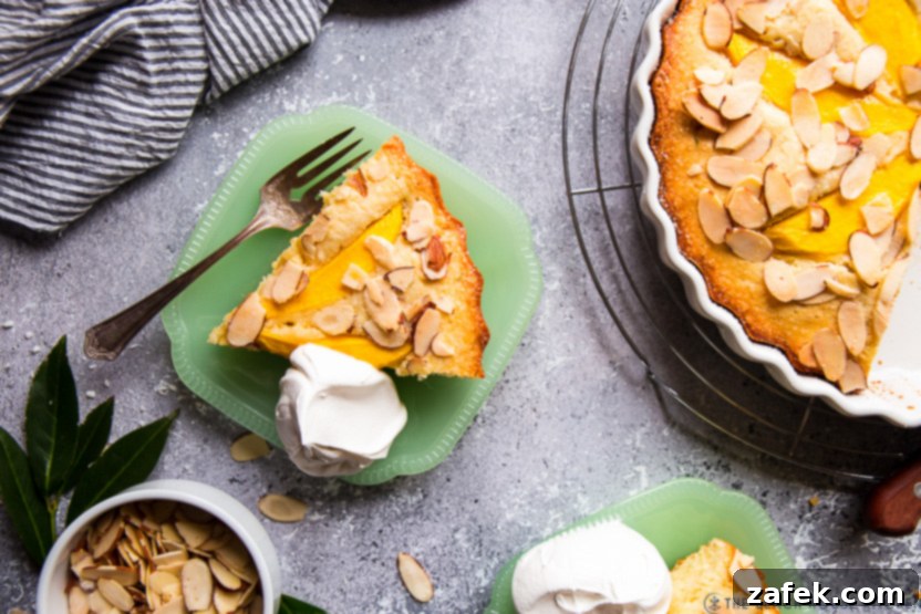 Overhead photo of a slice of tropical mango almond cake on a green plate, highlighting the moist interior and mango topping.