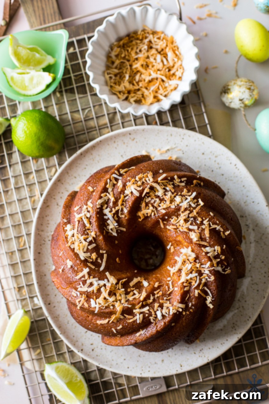 Overhead photo of Key Lime Coconut Bundt Cake on a plate on a wire rack with a bowl of toasted coconut