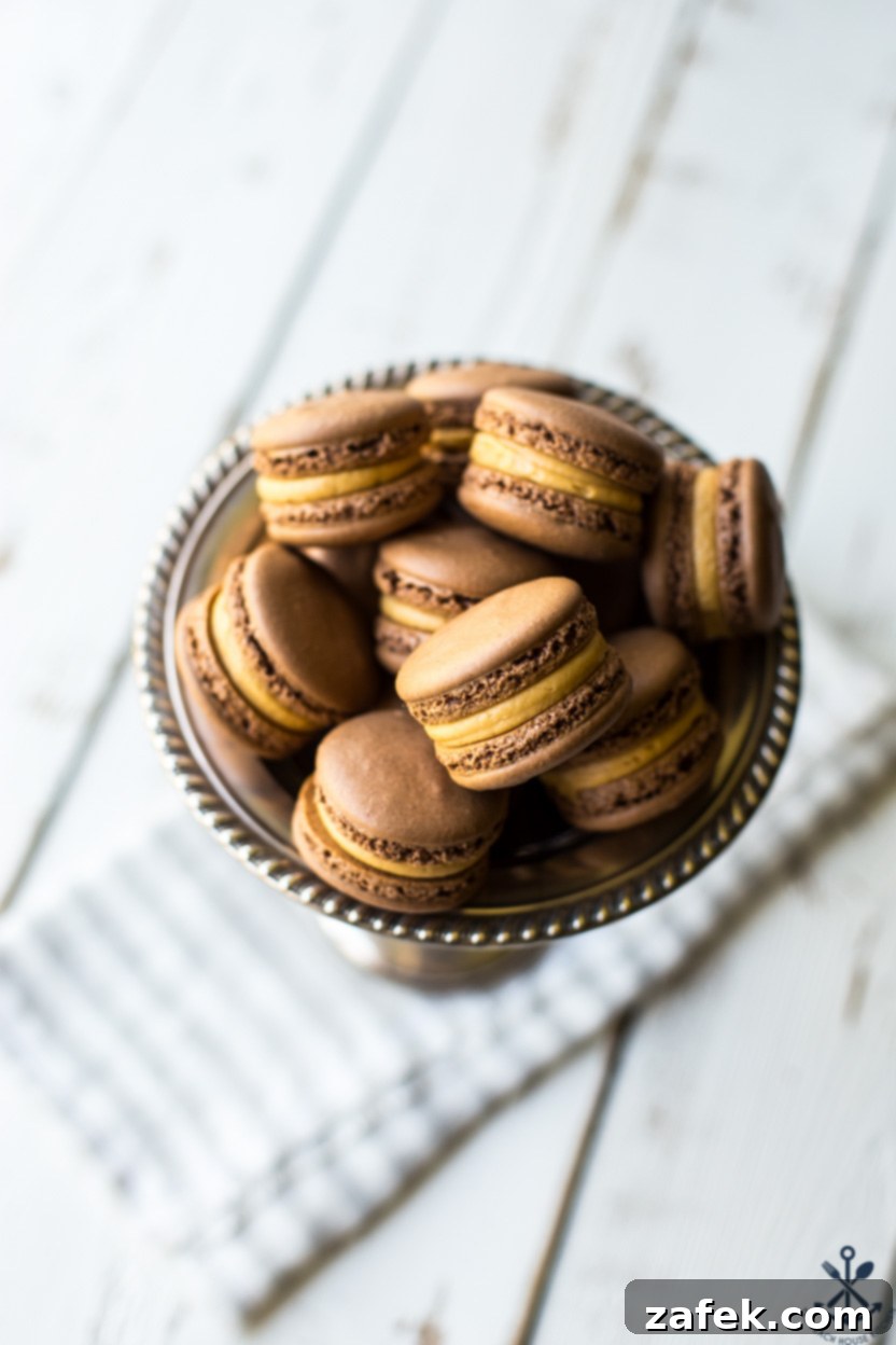 Irresistible Chocolate Peanut Butter Macarons 4 An overhead photo of perfectly baked chocolate peanut butter macarons resting in a sleek silver tray.