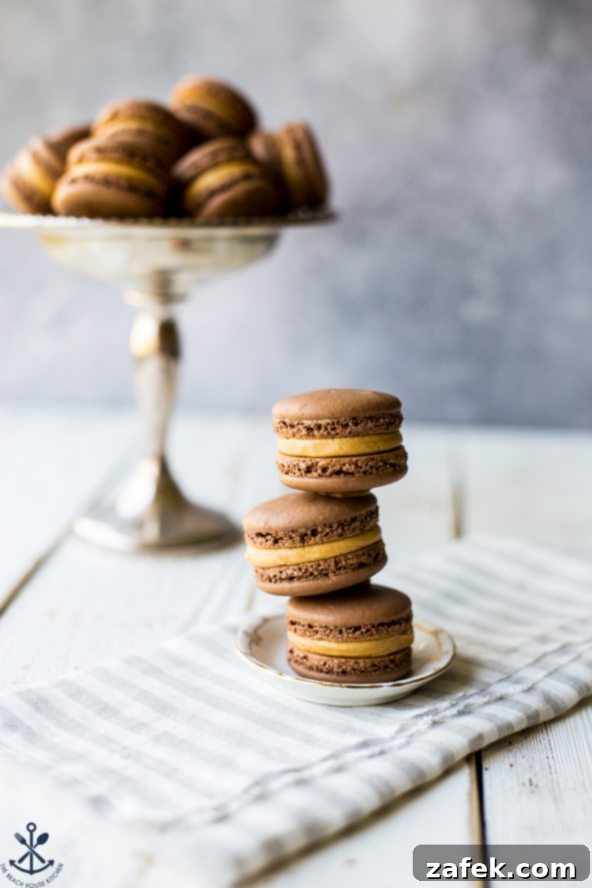 Irresistible Chocolate Peanut Butter Macarons 6 A small stack of three chocolate peanut butter macarons presented on a tiny, elegant plate.