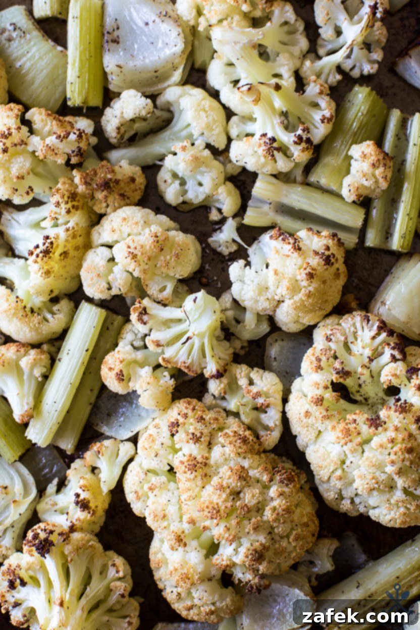 A tray of roasted cauliflower, onions, and celery, caramelized and tender after cooking, ready to be added to the soup base