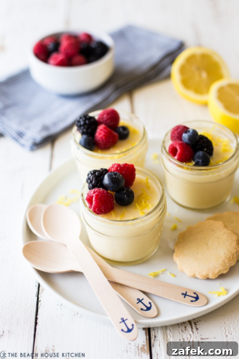 Jars of lemon posset on a plate with spoons and cookies
