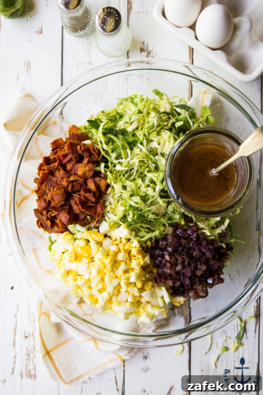 Shaved Brussels Sprouts Salad with Warm Bacon Dressing Ingredients for Shaved Brussels Sprouts Salad laid out: shaved sprouts, crispy bacon, hard-boiled eggs, and red onion.