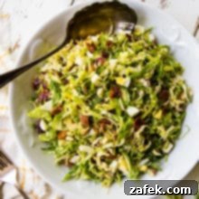 Crisp Shaved Brussels Salad with Warm Bacon Vinaigrette 2 Shaved Brussels Sprouts Salad with Warm Bacon Dressing recipe card image.