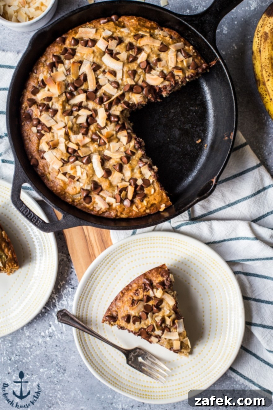 Coconut Chocolate Chip Skillet Banana Bread Overhead view of a cast iron skillet filled with freshly baked Coconut Chocolate Chip Banana Bread, generously topped with chocolate chips and toasted coconut.