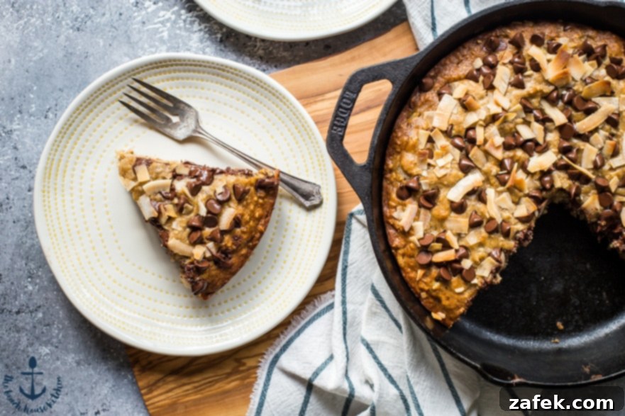 Coconut Chocolate Chip Skillet Banana Bread A perfectly portioned slice of Coconut Chocolate Chip Skillet Banana Bread on a white plate, showcasing its fluffy texture and rich inclusions.