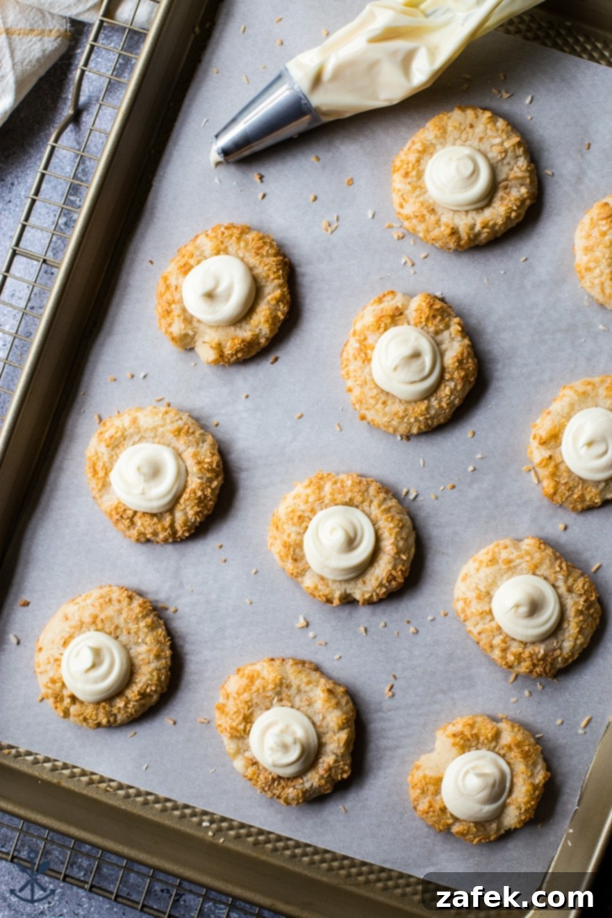 Creamy Coconut Thumbprint Bites 3 Overhead photo of a baking sheet with thumprint cookies with white frosting