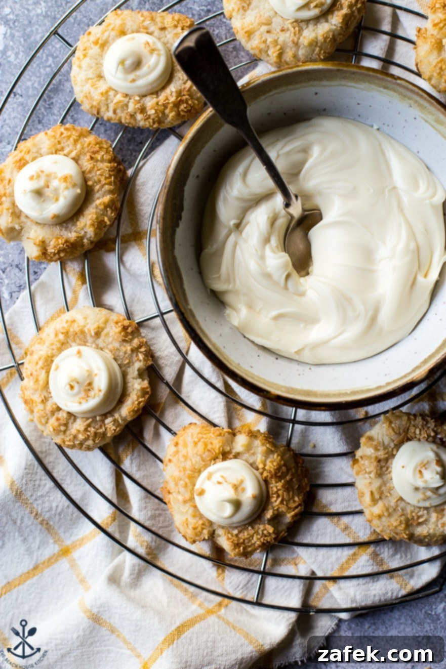Creamy Coconut Thumbprint Bites 4 Up close overhead photo of thumbprint cookies on a wire rack with a bowl of frosting