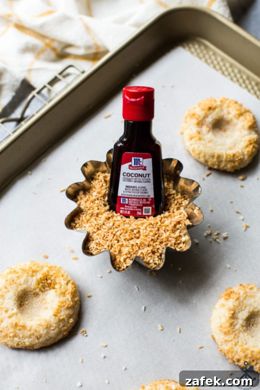 Creamy Coconut Thumbprint Bites 5 A bowl of toasted coconut with a bottle of coconut extract