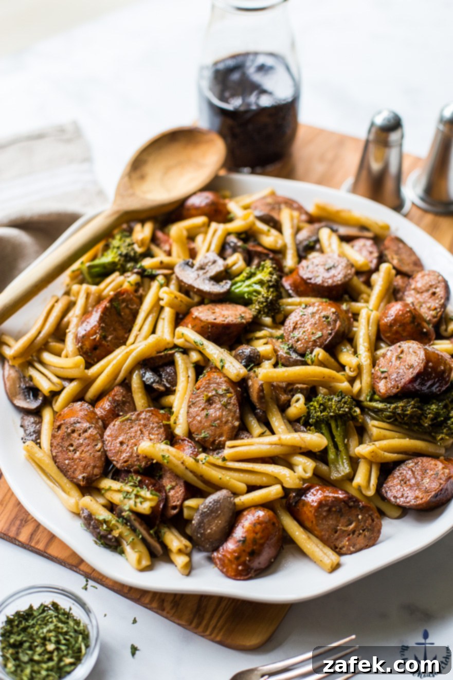 A beautifully plated dish of balsamic pasta with savory chicken sausage, tender broccoli florets, and earthy mushrooms.