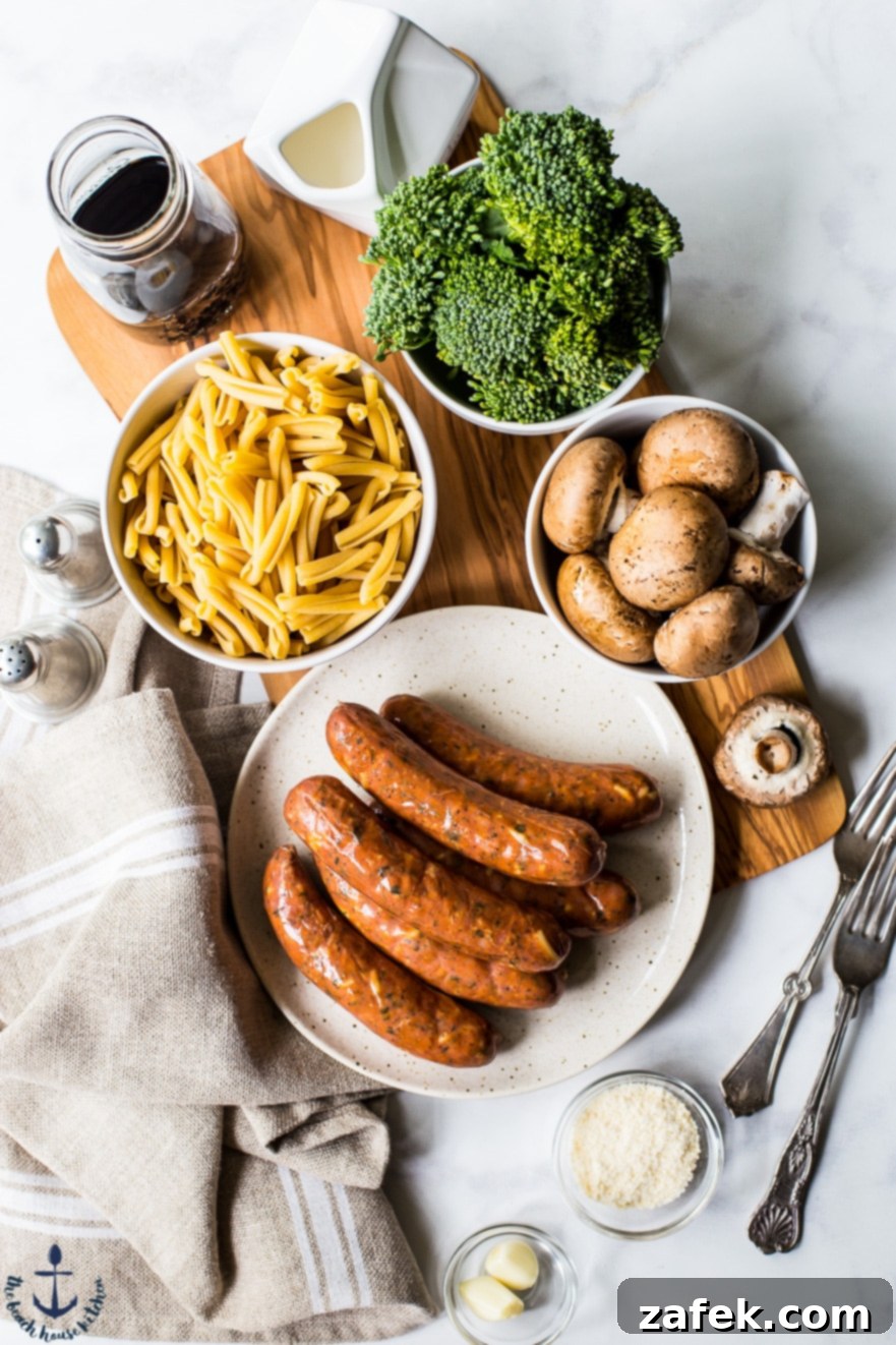 Overhead photo of fresh, vibrant ingredients for a balsamic pasta dish: raw chicken sausage, broccoli florets, sliced mushrooms, and herbs.