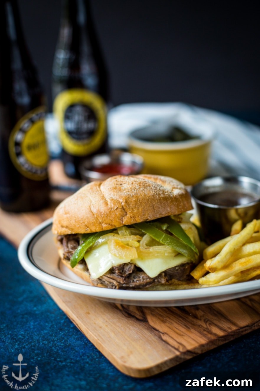 Philly French Dip Sandwiches with Peppers, Onions and Land O'Lakes Deli American Cheese Close-up of a perfectly toasted Kaiser roll filled with savory roast beef, vibrant sautéed peppers and onions, and three slices of gooey Land O'Lakes Deli American cheese.