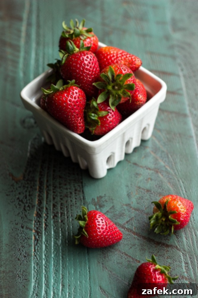 Strawberry Shortcake Macaron Dreams 3 A bowl of fresh strawberries with three of them having fell off it