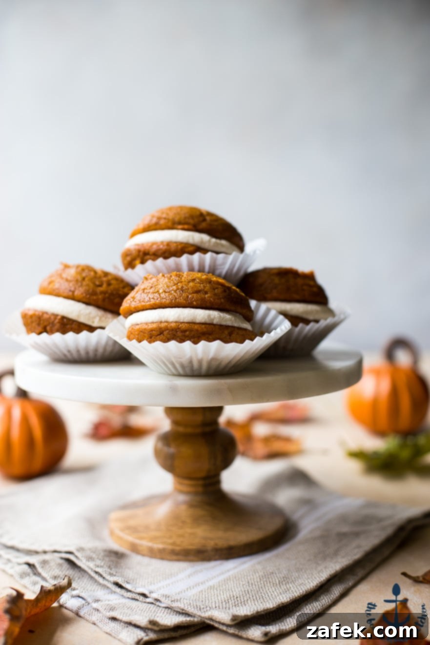Pumpkin Whoopie Pies with Maple Buttercream Pumpkin Whoopie Pies with Maple Buttercream on a marble cake stand with pumpkins in the background