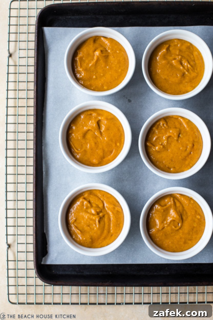 Overhead photo of six ramekins filled with a pre-baked pumpkin cake batter