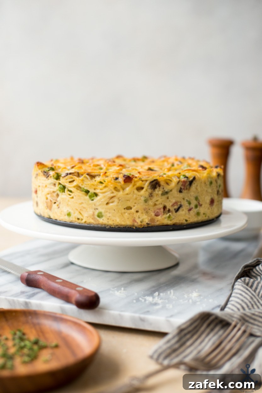 Hearty Pancetta, Mushroom & Pea Spaghetti Pie 3 A beautifully presented spaghetti pie on a white pedestal, ready to be served