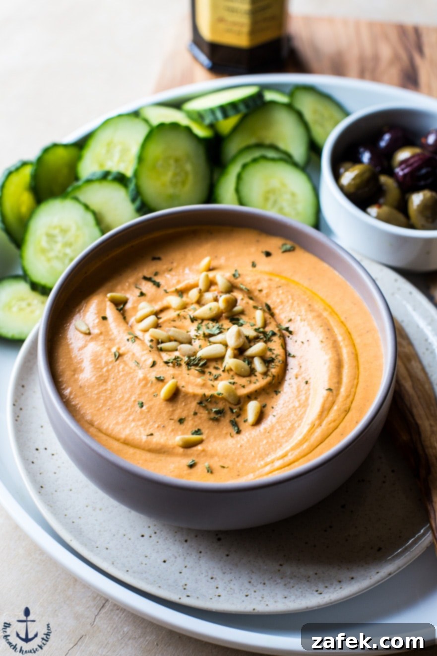 Close-up of White Bean Roasted Red Pepper Hummus with a rustic spoon.