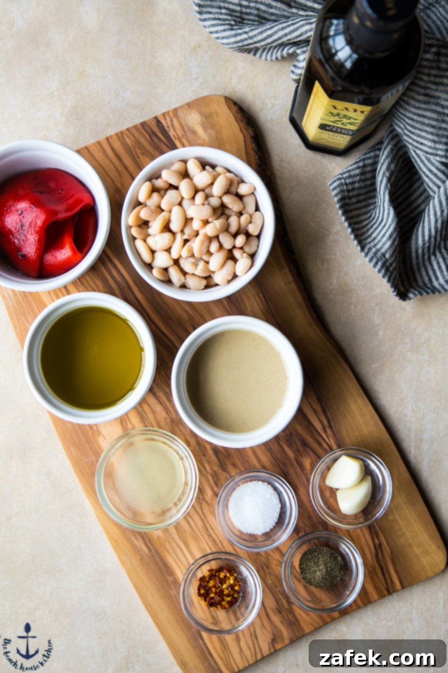 White Bean Roasted Red Pepper Hummus garnished with fresh parsley and olive oil, with crackers.