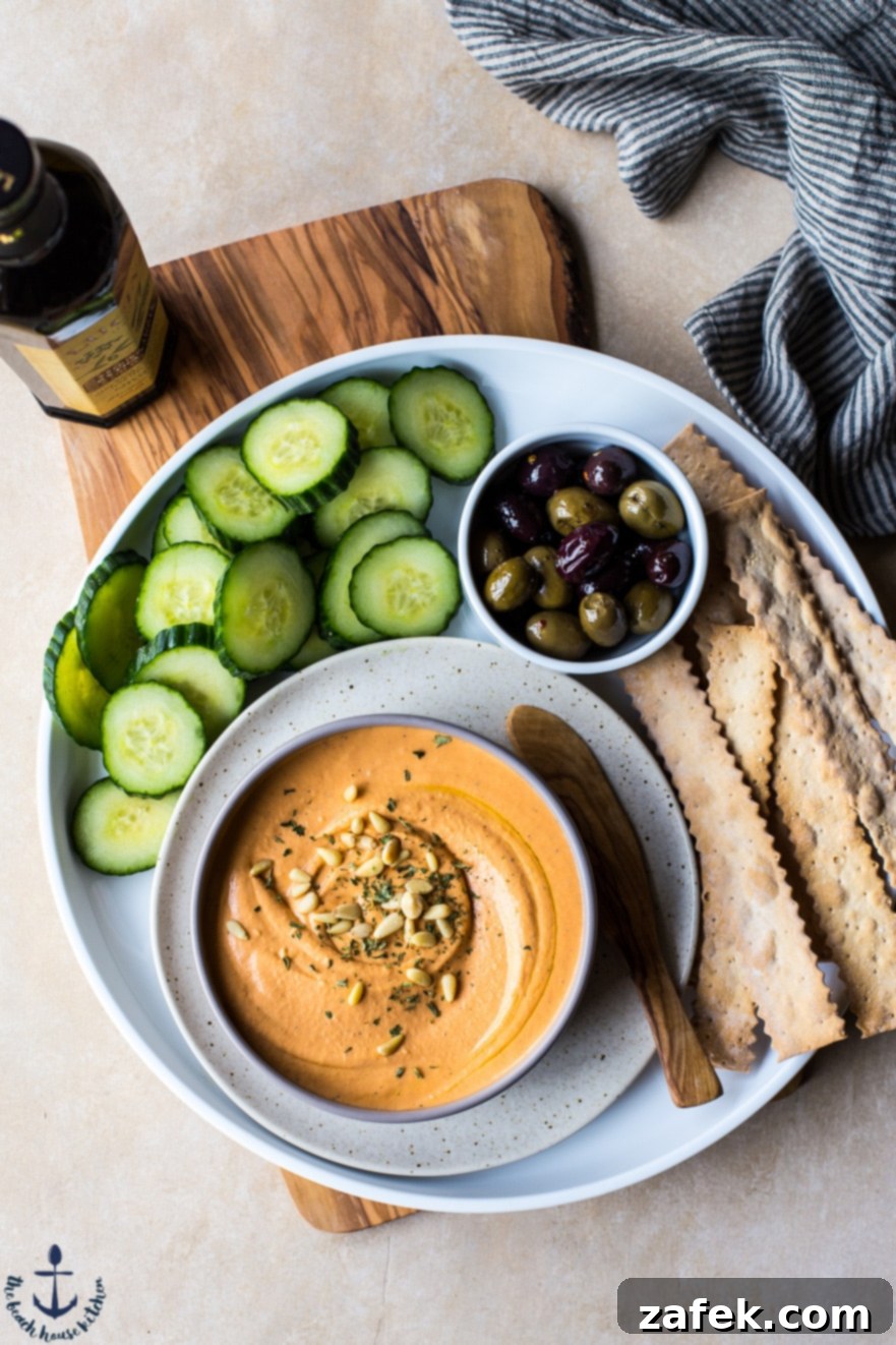 A close-up of a bowl of White Bean Roasted Red Pepper Hummus, ready to be enjoyed.