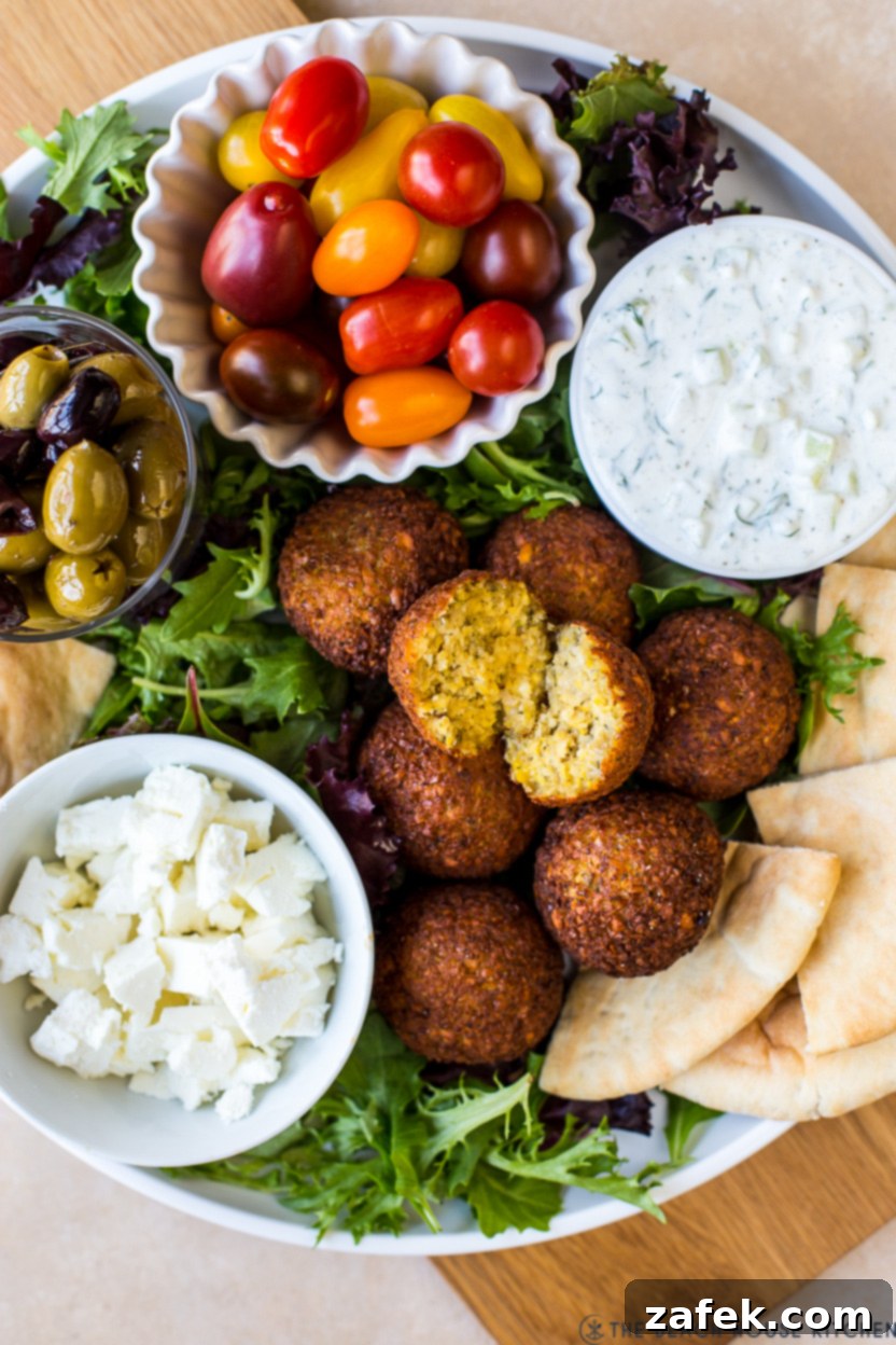 Up close overhead photo of a falafel platter with tzatziki sauce, tomatoes, feta, pita and olives