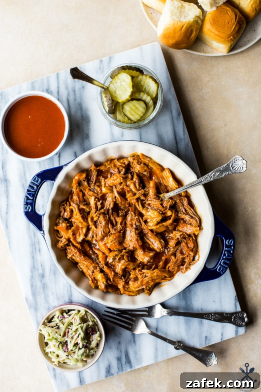 Sticky Sweet Heat Chicken Sliders 3 A vibrant selection of ingredients for hot honey pulled chicken sliders laid out in a baking dish and small bowls on a marble board, including chicken, hot sauce, honey, brown sugar, and butter