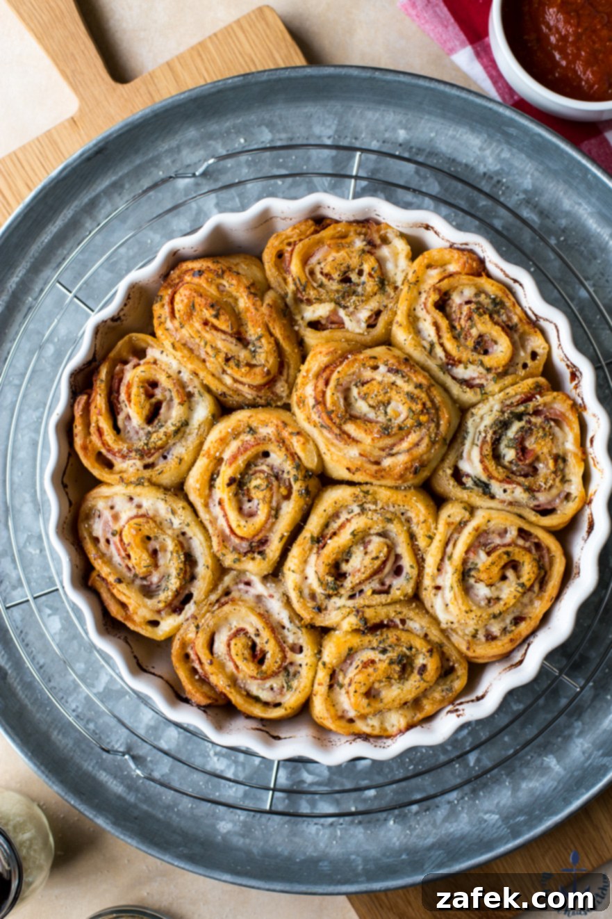 Overhead photo of Sharp Italian Pinwheels arranged on a silver tray with a bowl of marinara sauce for dipping