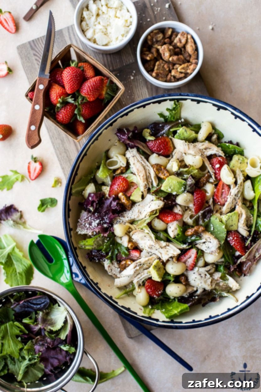 Vibrant Chicken Strawberry Avocado Pasta Salad with Creamy Poppy Seed Dressing in a large white bowl, garnished with fresh herbs.