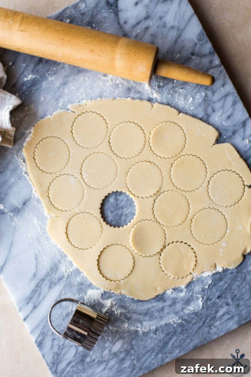 Copycat Twix Cookies 4 Overhead photo of cookie dough with cut outs and a rolling pin on a marble board