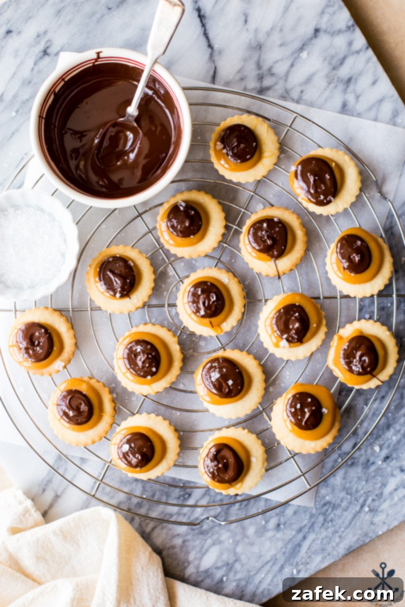 Copycat Twix Cookies 8 Overhead photo of Twix cookies on a round wire rack with a bowl of melted chocolate and a small bowl of sea salt