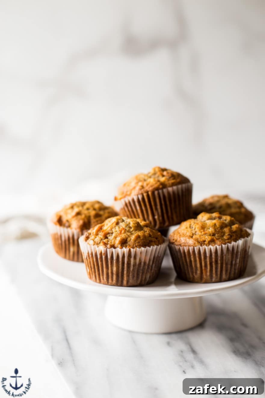 Sunrise Harvest Muffins 3 Morning glory muffins beautifully arranged on a rustic cake stand, highlighting their golden tops and varied textures.