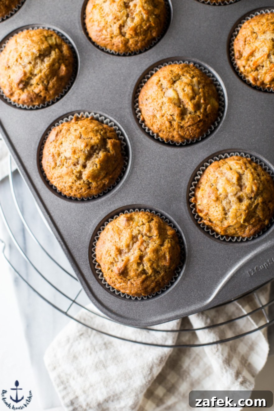 Sunrise Harvest Muffins 4 Close-up overhead view of freshly baked Morning Glory Muffins in a muffin tin, showing the delightful mix of ingredients peeking through.