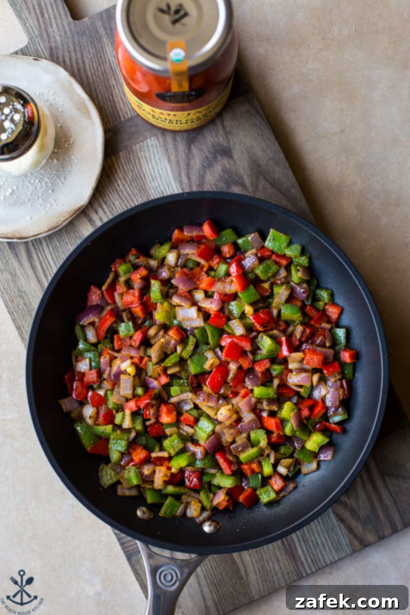Overhead photo of a skillet of cooked red onions and red and green bell peppers, slightly softened and colorful