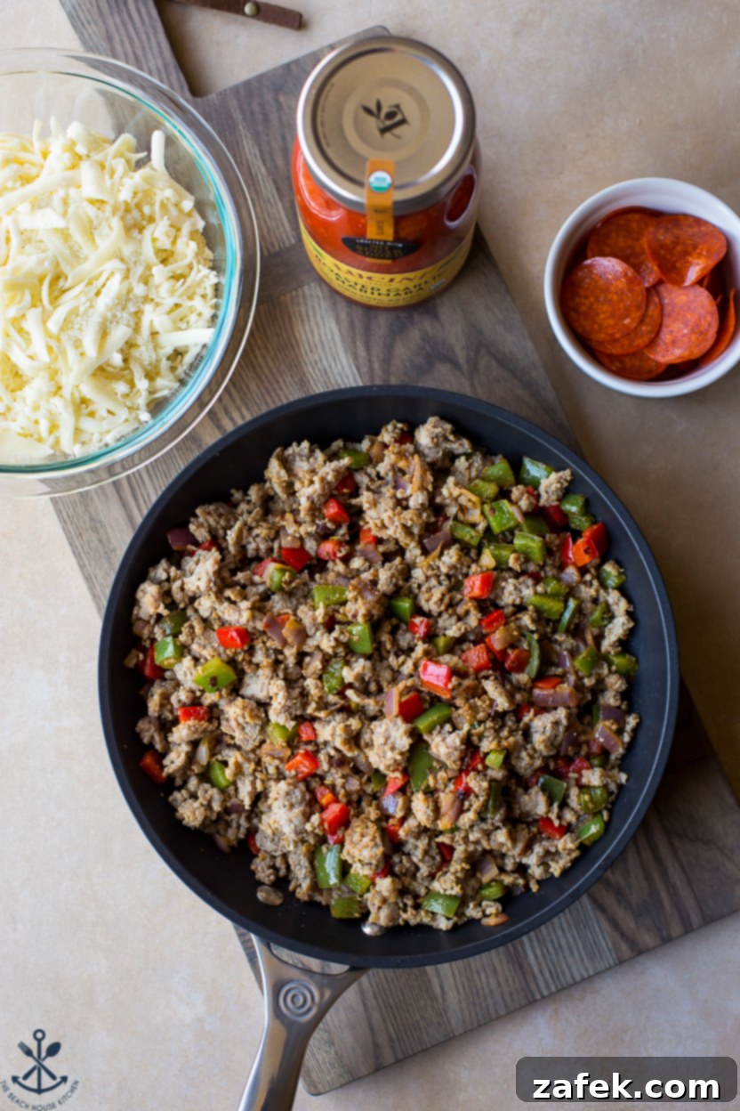 Overhead photo of a skillet of cooked peppers, onions, and Italian sausage, ready to be added to the mac and cheese