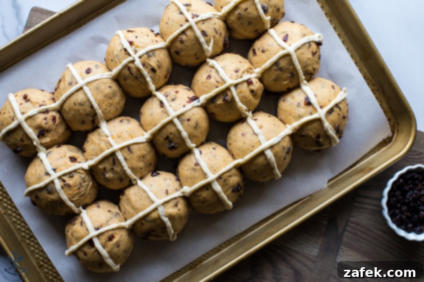 Spiced Easter Buns 5 A baking sheet filled with unbaked Hot Cross Buns, each adorned with a distinct white cross, ready for the oven.