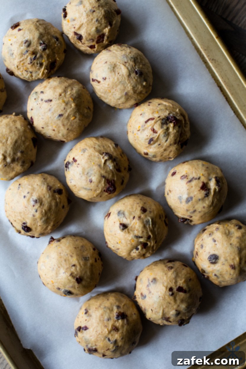 Spiced Easter Buns 7 A close-up, overhead shot of portioned and rounded Hot Cross Bun dough balls, neatly arranged on a baking sheet, awaiting their second rise.