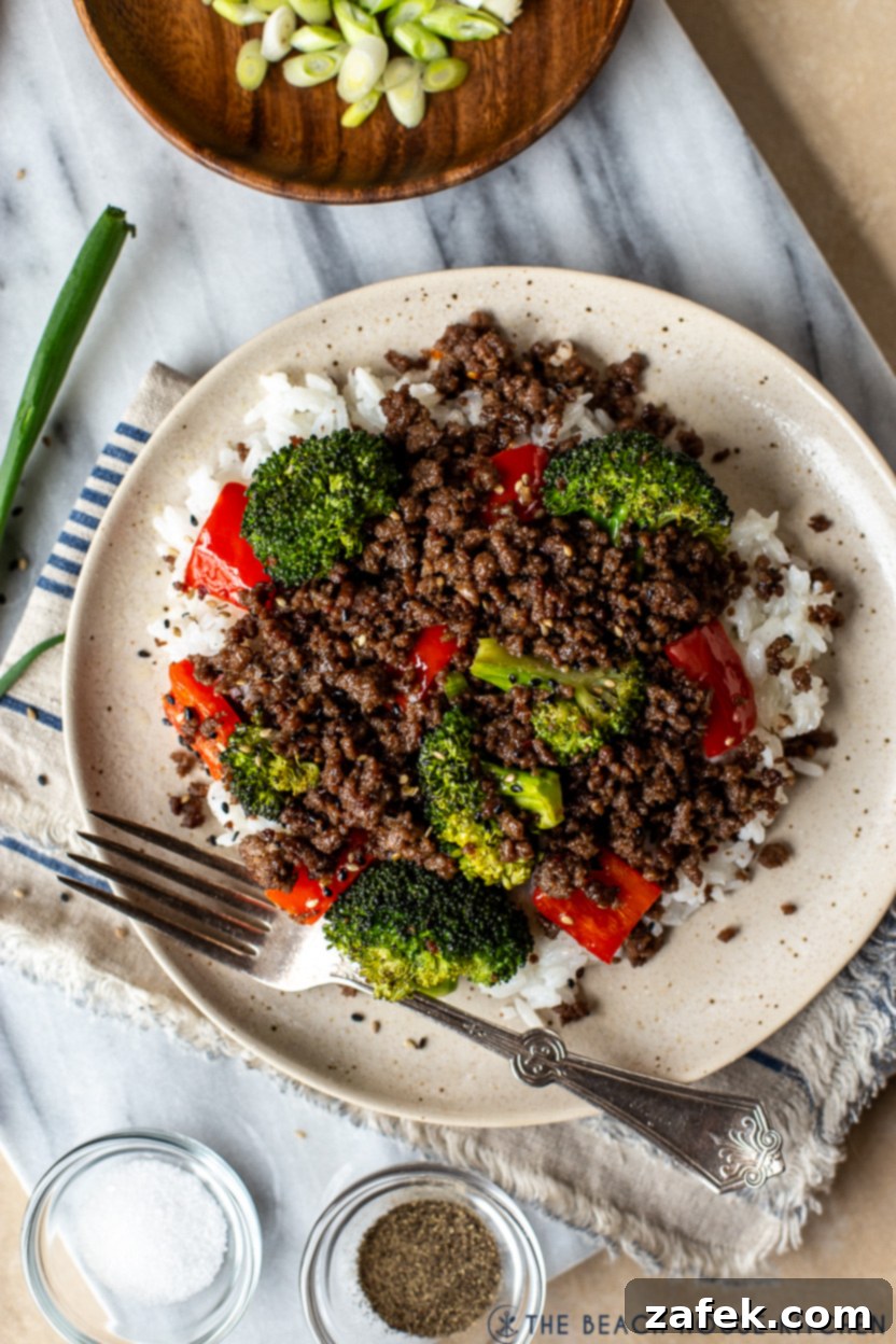 Very up close photo of a plate of beef, broccoli and red peppers over rice